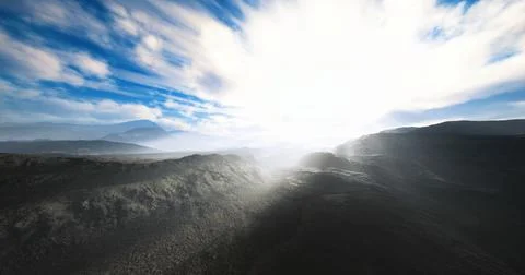 Bright sunlight filters through clouds over a mountainous landscape in daylig Ilustração Stock