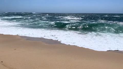 Bright sunlight glinting on the ocean surface as waves break on sandy beach Stock Footage 240671283