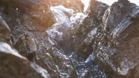 Bright sunlight glowing through wet rocks near the ocean shore Stock Footage 337417131