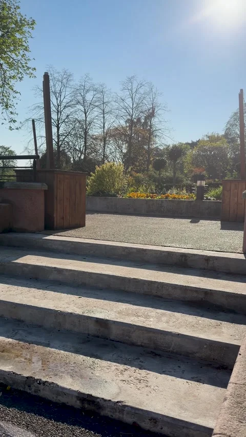 Bright sunlight illuminates stone staircase and urban garden scene Stock Footage 346670522