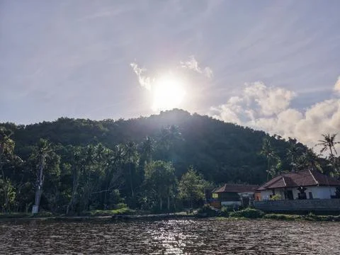 Bright Sunlight over Mountain Lake Village with Palm Trees 库存照片