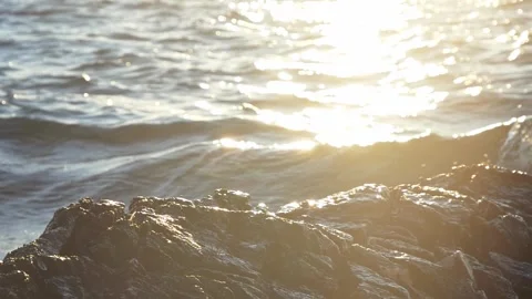 Bright sunlight reflecting over ocean waves and dark coastal rocks. Stock Footage 337408852