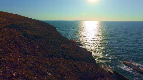 Bright sunlight reflection on ocean surface near rocky coast Stock Footage 340450285