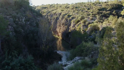 Bright sunlight streaming across winding river flowing between rocky canyon Video stock 306686954