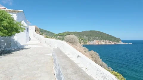 A bright, sunlit scene featuring a traditional whitewashed church and stone Stock Footage 346667072