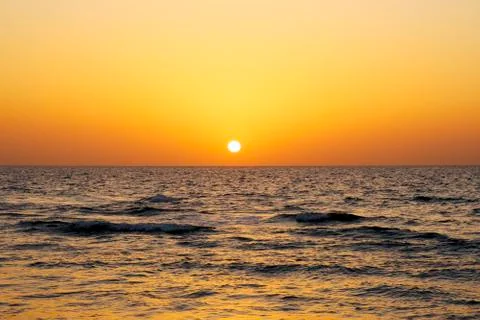 A bright sunset in a cloudless sky on the Mediterranean Sea with waves in Isr Stock Photos