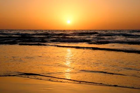 A bright sunset in a cloudless sky on the Mediterranean Sea with waves in Isr Stock Photos