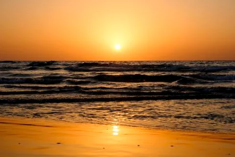 A bright sunset in a cloudless sky on the Mediterranean Sea with waves in Isr Stock Photos
