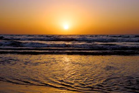 A bright sunset in a cloudless sky on the Mediterranean Sea with waves in Isr Stock Photos