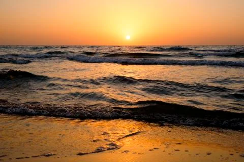 A bright sunset in a cloudless sky on the Mediterranean Sea with waves in Isr Stock Photos