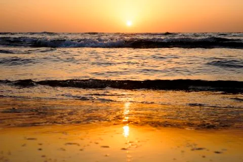 A bright sunset in a cloudless sky on the Mediterranean Sea with waves in Isr Stock Photos