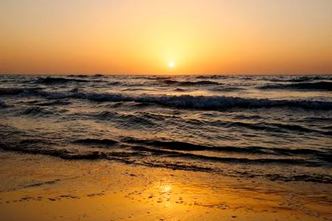 A bright sunset in a cloudless sky on the Mediterranean Sea with waves in Isr Stock Photos