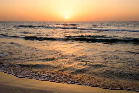 A bright sunset in a cloudless sky on the Mediterranean Sea with waves in Isr Stock Photos