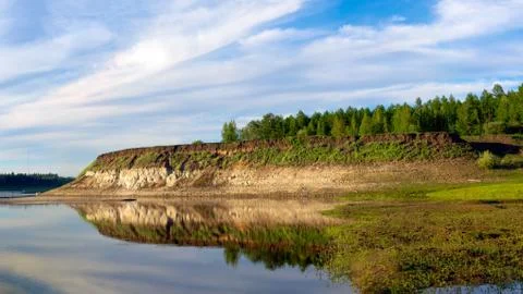 A bright sunset with clouds reflected in the water in Yakutia with clay cliff Stock-Fotos