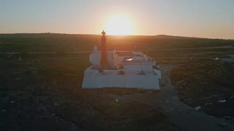 Bright sunset light shining at high seaside lighthouse aerial view. Red beacon Fotos de archivo