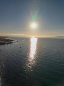 Bright Sunset Over Ocean Surface Near Coastal Resort Town Stock-Fotos