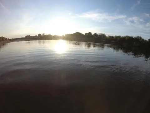 Bright sunset reflection on calm river surface Stock Photos