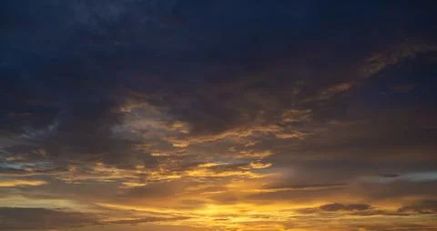 Bright sunset with setting sun behind vivid orange and yellow clouds Stock Photos