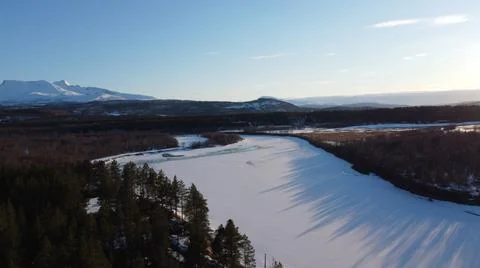Bright sunset sunlight over deep norwegian forest and frozen river landscape Foto stock