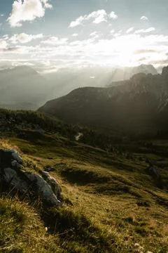 Bright sunshine is filtering through the clouds above the mountains Stock Photos