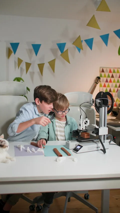 At a bright table, two schoolchildren watch a 3D printer work and play with it Stock Footage 335392111