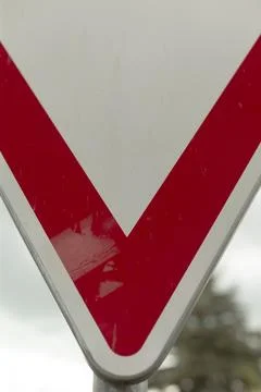 Bright triangular warning sign against cloudy and blurred background Stock Photos
