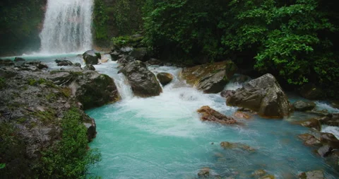 Bright turquoise river and waterfall in Costa Rica rainforest viewed during Stock Footage 341363741