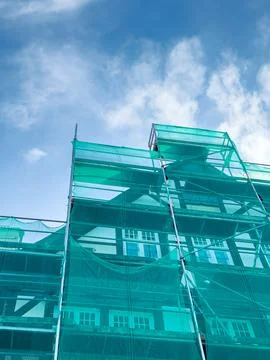 Bright turquoise scaffolding frames a building under renovation, contrastin.. 库存照片