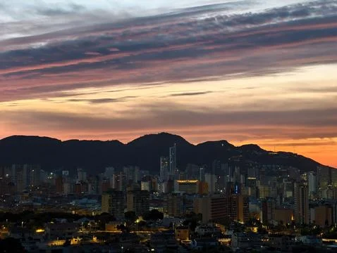 Bright twilight city view featuring dynamic cloud patterns above bustling u.. Stock Photos