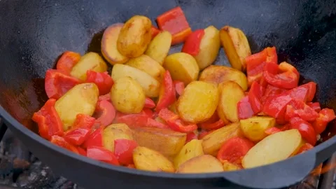 Bright vegetables are fried in a cauldron over an open fire. Vegetables are Stock Footage 278868377