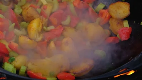Bright vegetables are fried in a cauldron over an open fire. Vegetables are Video stock 279271891