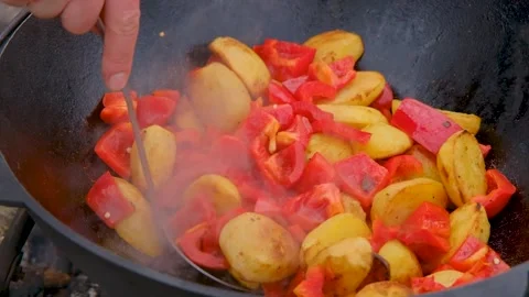 Bright vegetables are fried in a cauldron over an open fire. Vegetables are Stock Footage 280213764