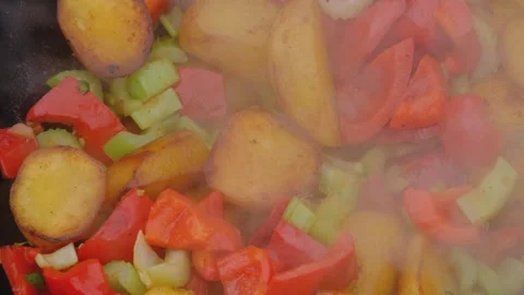 Bright vegetables are fried in a cauldron over an open fire. Vegetables are Stock Footage 280213847