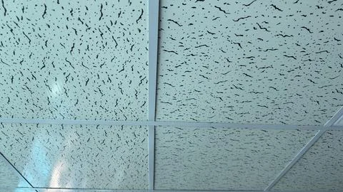 A bright view of a modern dropped ceiling featuring square panels with a dist Stock Photos