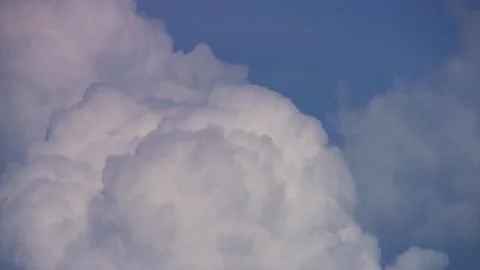 Bright white clouds bubble against a clear blue sky Stock Footage 329755644