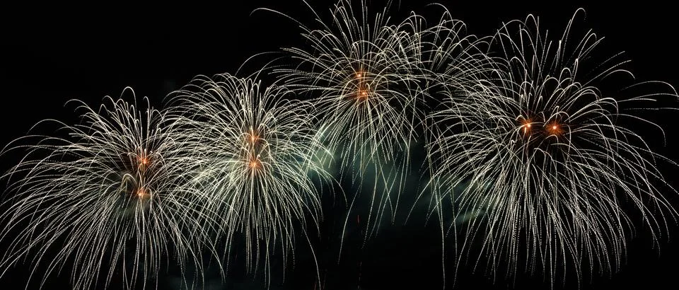 Bright White Fireworks Exploding In The Night Sky Wide Shot Stock Photos