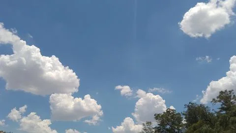 Bright white fluffy clouds floating in a vibrant blue sky Stock Photos