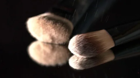Bright white sparkling glitter falling on makeup brushes on the black background Stock Footage 75969156