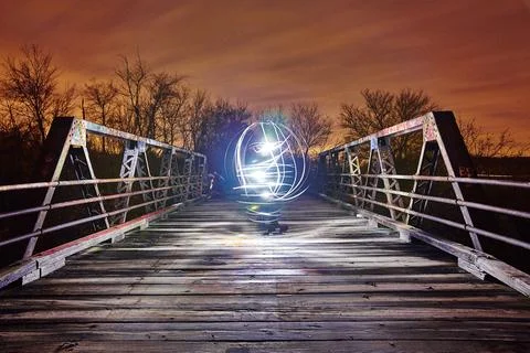 Bright white sphere of light illuminates a white bridge at twilight Stock Photos