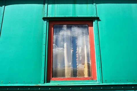 Bright window reflects clear sky in vibrant green building facade 스톡 사진