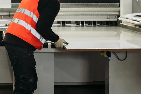In a bright workspace, a diligent worker in a safety vest carefully aligns a  Stock Photos