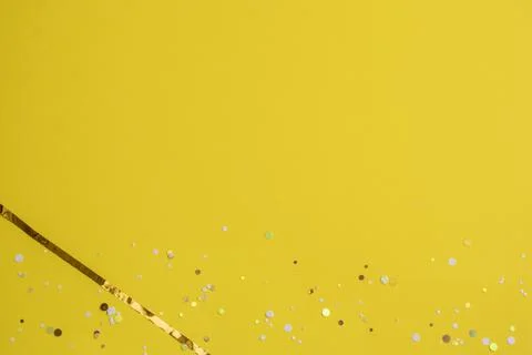 Bright yellow abstract background with round sequins and gold ribbon to the side Stock Photos