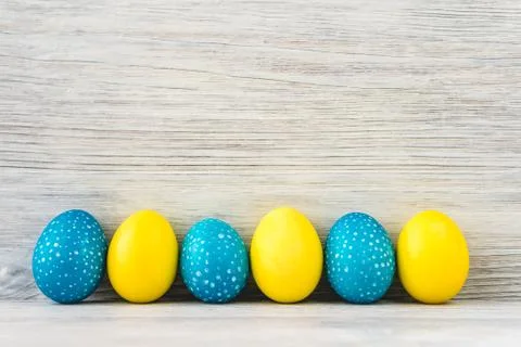 Bright yellow and blue Easter eggs on white wooden background Stock Photos