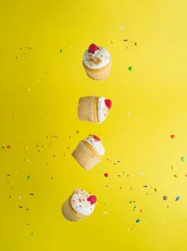 On a bright yellow background with multi-colored confetti, muffins with cream Foto stock