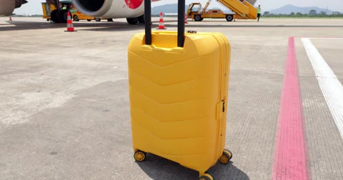 Bright yellow carry on suitcase standing on sunny airport tarmac close shot Vídeos de archivo 345716853