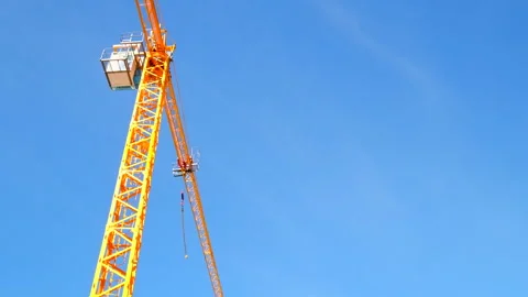 Bright yellow construction crane stands out against blue sky, upward view Stock Footage 304303783