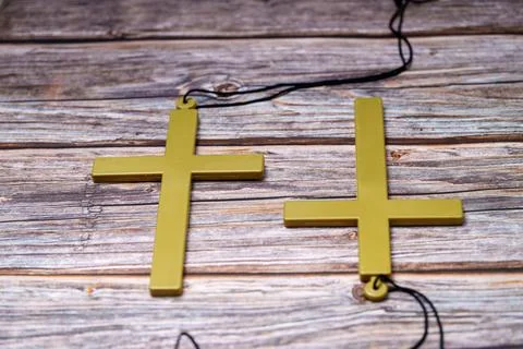 Bright yellow crosses hanging from string on wooden surface in a simple setti Photos