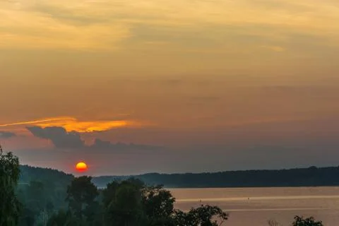 Bright yellow disk of the setting sun against the background of a cloudy sky. Stock Photos