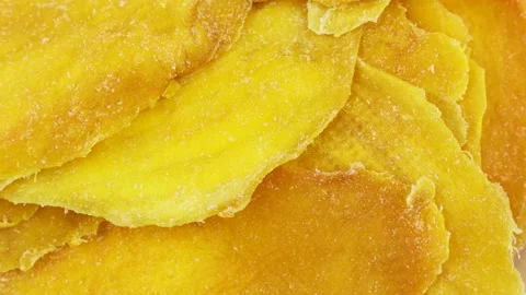 Bright yellow dried mango slices rotation close up top view Stock Footage 239027628