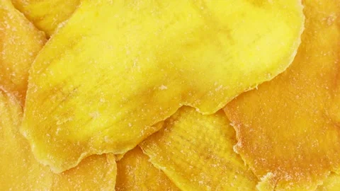 Bright yellow dried mango slices rotation close up top view Video stock 239661857